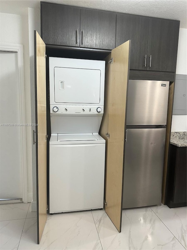 laundry area with stacked washer / drying machine and a textured ceiling