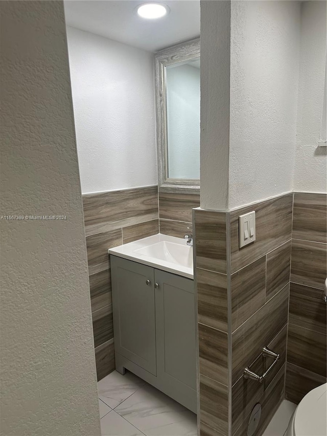 bathroom featuring vanity, tile walls, and toilet