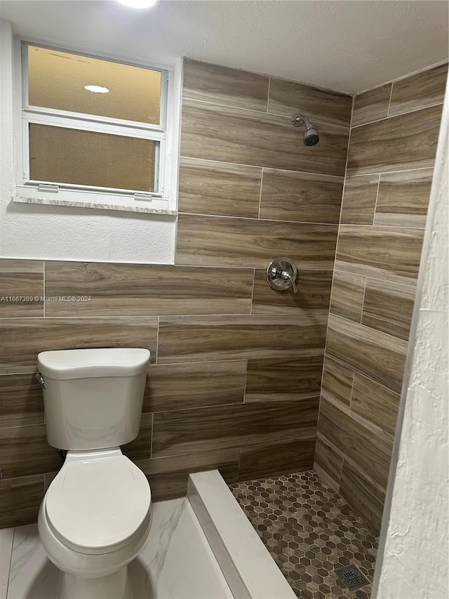 bathroom featuring tile walls, tiled shower, and toilet