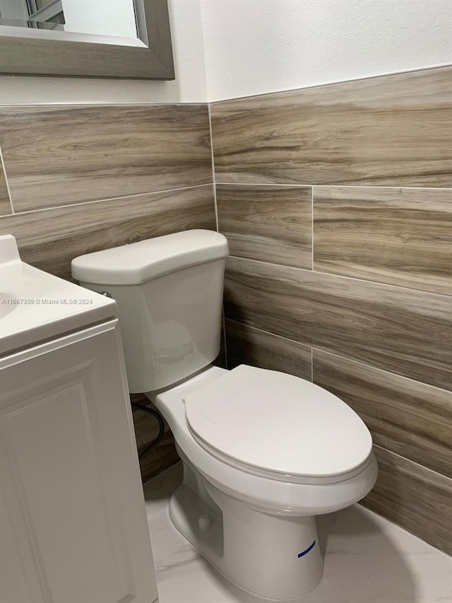 bathroom featuring tile walls, vanity, and toilet