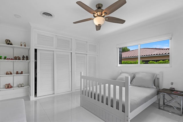 tiled bedroom featuring ceiling fan, a closet, and ornamental molding