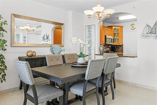 dining area with an inviting chandelier, light tile patterned flooring, and crown molding