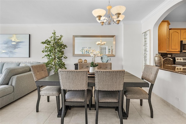 dining room with an inviting chandelier, light tile patterned floors, and crown molding