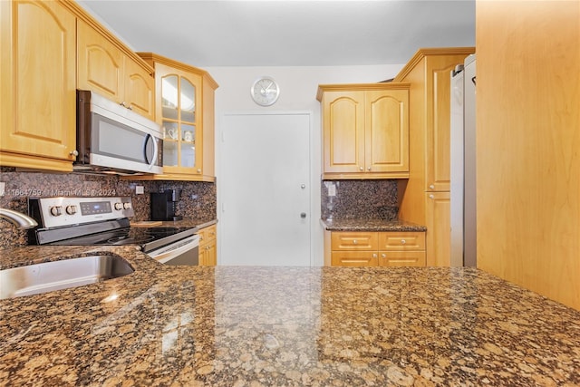 kitchen with dark stone counters, light brown cabinets, and stainless steel appliances