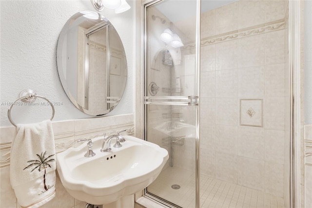 bathroom featuring walk in shower, tile walls, and sink