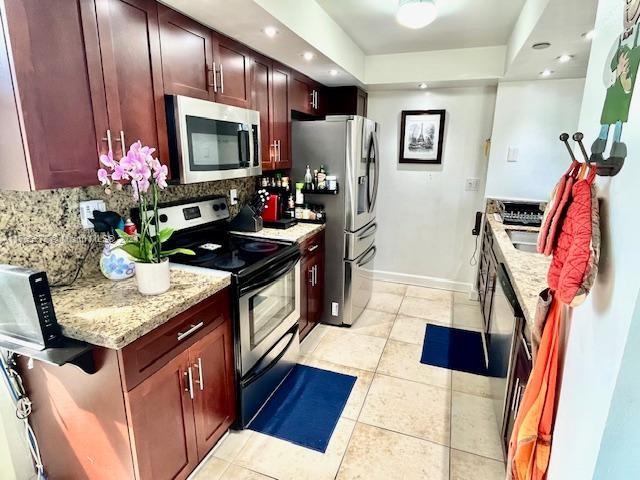 kitchen featuring light stone countertops, appliances with stainless steel finishes, light tile patterned floors, and decorative backsplash