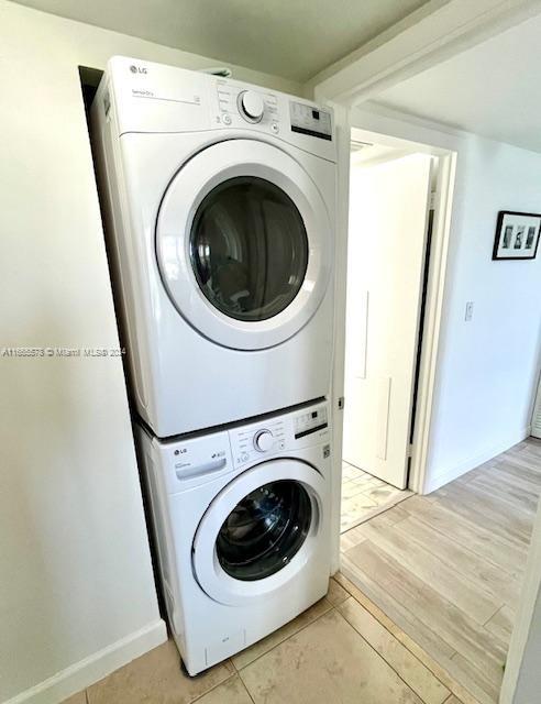 clothes washing area with light wood-type flooring and stacked washing maching and dryer