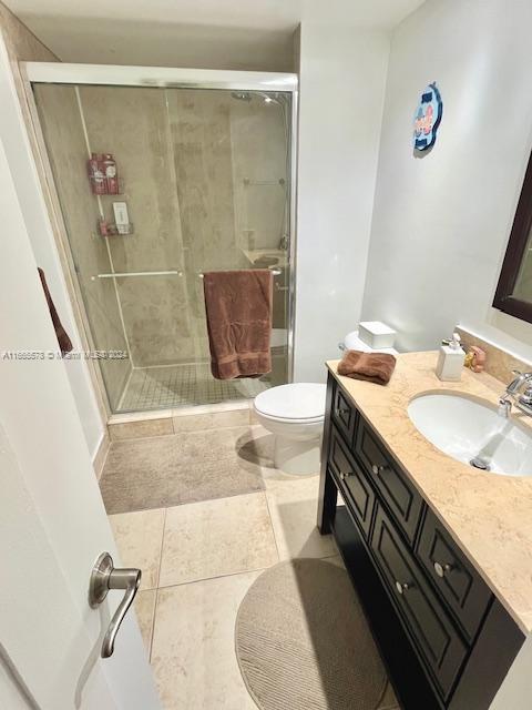 bathroom with vanity, a shower with shower door, toilet, and tile patterned floors