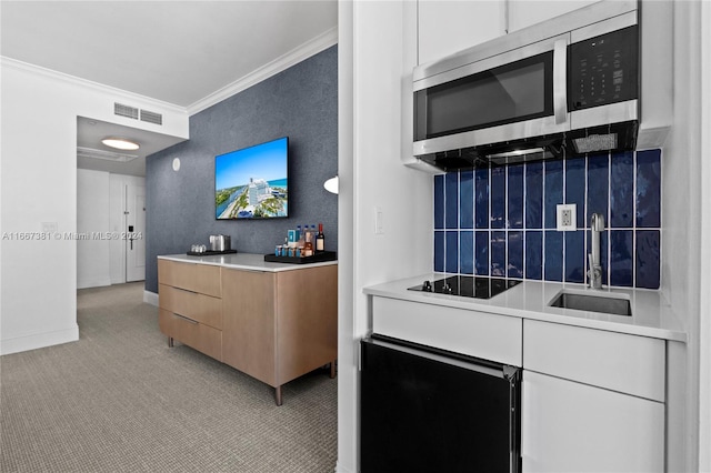 kitchen with black electric stovetop, light colored carpet, crown molding, and sink