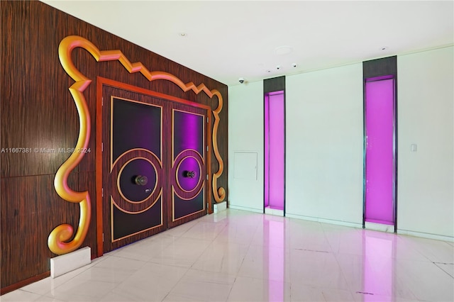 misc room with wooden walls and light tile patterned flooring