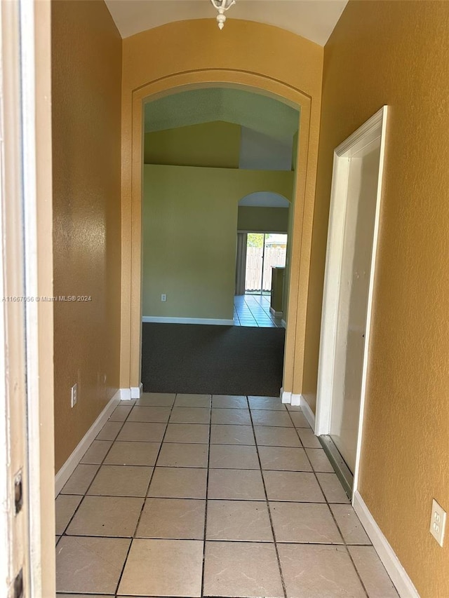 hallway with vaulted ceiling and light tile patterned floors