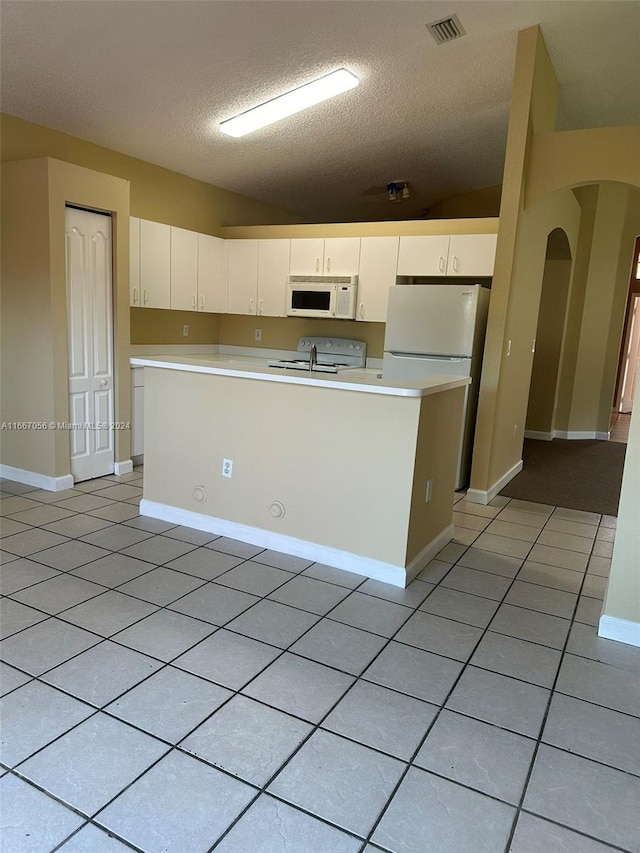 kitchen featuring white cabinets, a textured ceiling, a center island with sink, and white appliances