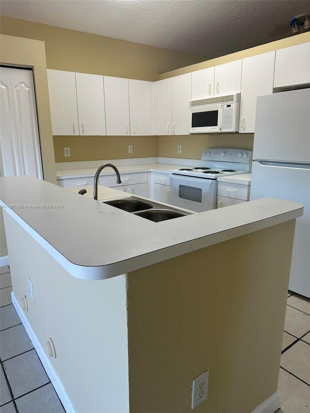 kitchen featuring sink, a kitchen island with sink, white appliances, and white cabinets