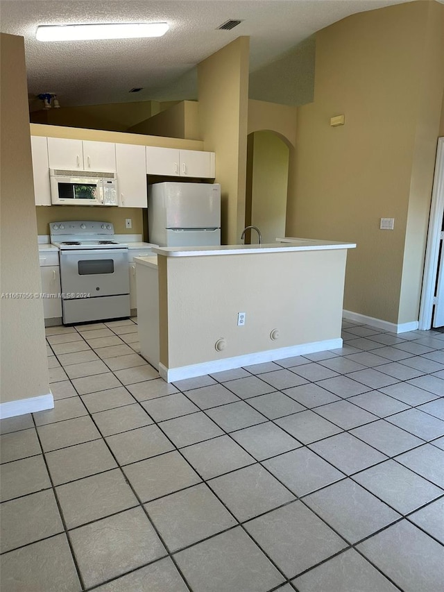 kitchen featuring white appliances, a textured ceiling, vaulted ceiling, and white cabinets