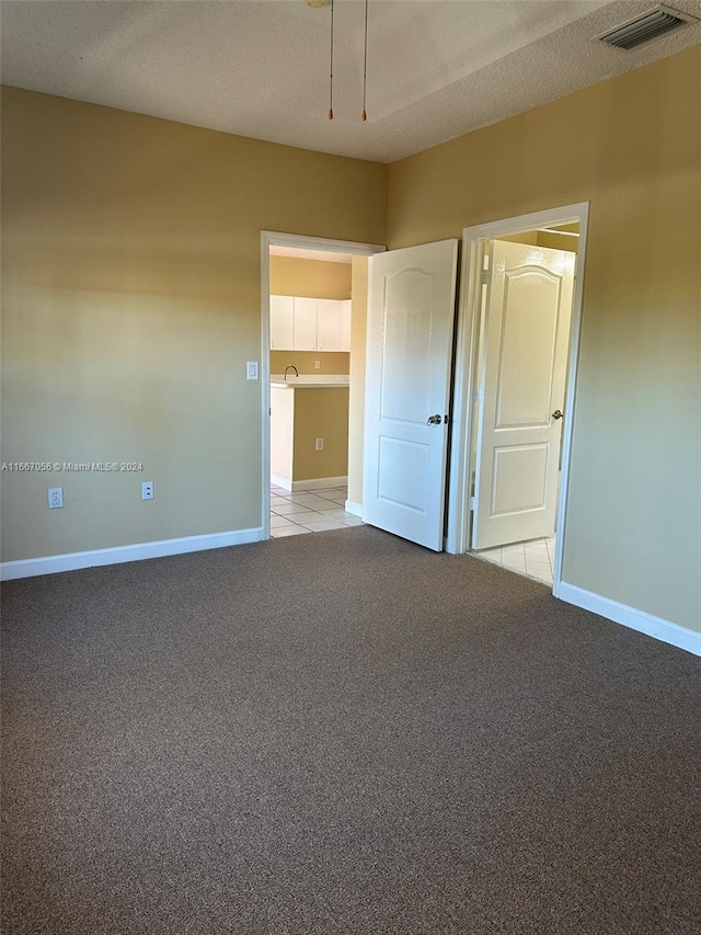 unfurnished bedroom featuring light carpet and a textured ceiling