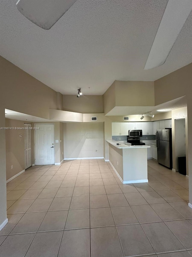 kitchen featuring a textured ceiling, white cabinets, kitchen peninsula, appliances with stainless steel finishes, and light tile patterned floors