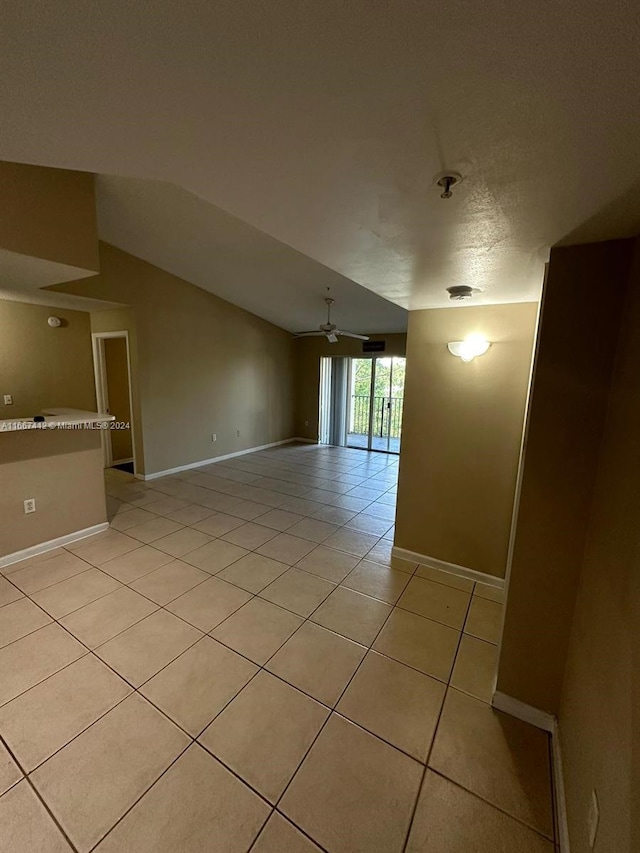 empty room featuring vaulted ceiling, ceiling fan, light tile patterned floors, and a textured ceiling