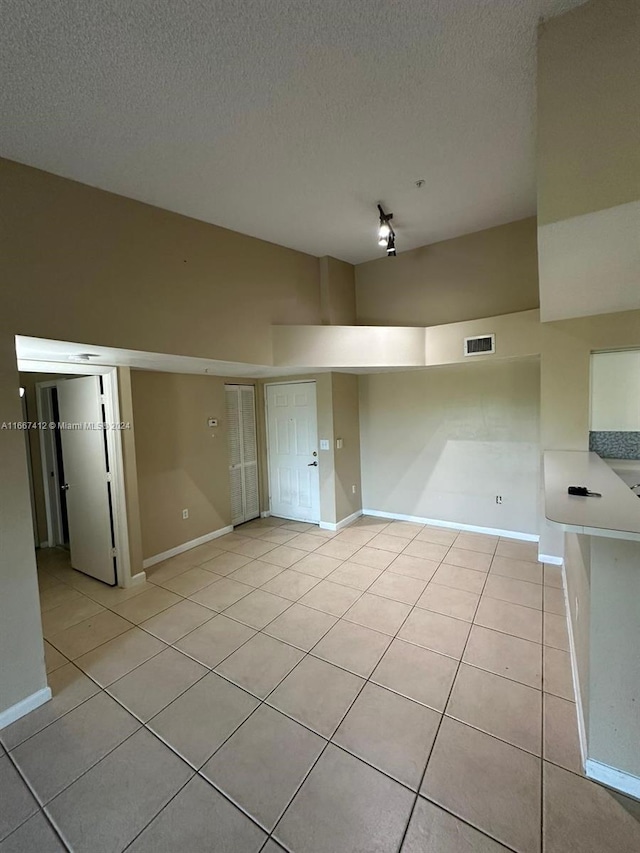 tiled empty room with a textured ceiling