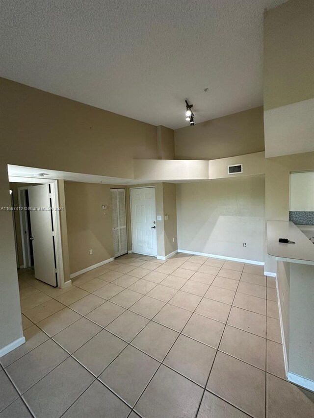 4848 N State Road 7 Unit 4305, Coconut Creek, FL 33073 - empty room with light tile patterned flooring, a textured ceiling, and rail lighting