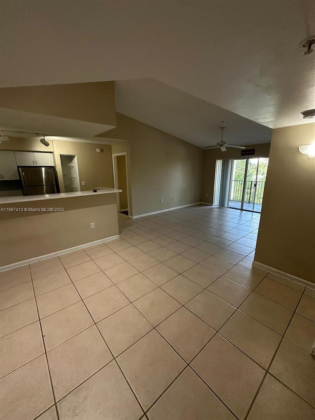 empty room with ceiling fan, lofted ceiling, and light tile patterned floors