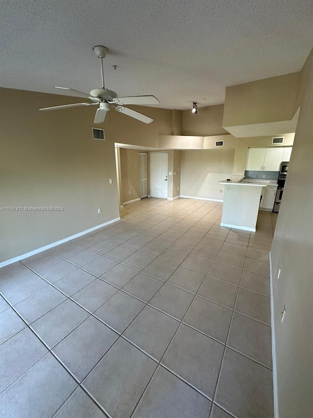 interior space featuring light tile patterned floors, a textured ceiling, and ceiling fan