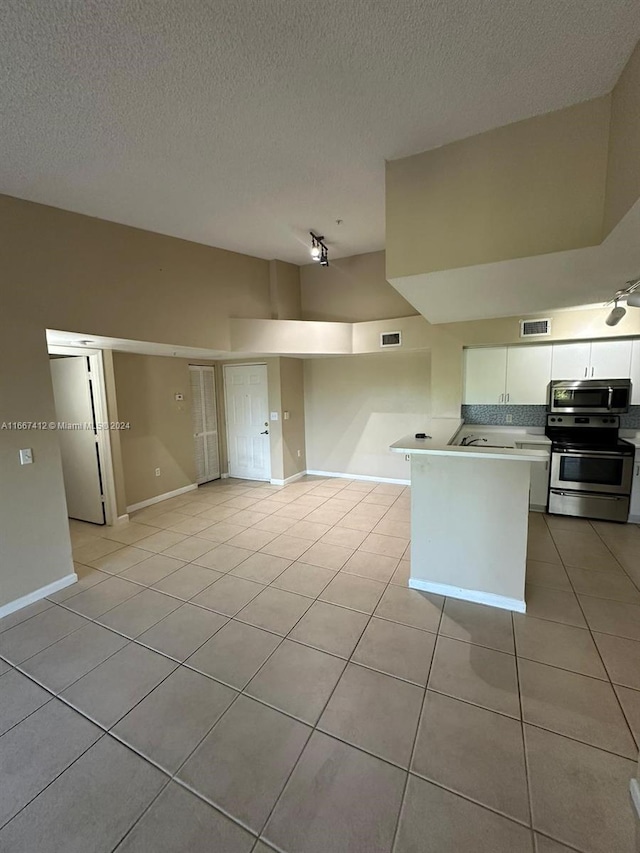 kitchen featuring white cabinets, a textured ceiling, appliances with stainless steel finishes, and light tile patterned floors