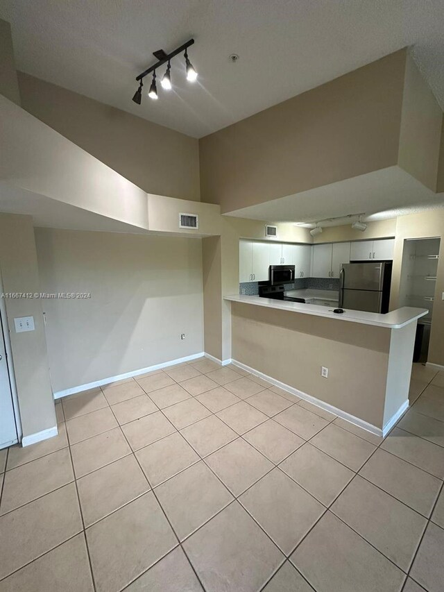4848 N State Road 7 Unit 4305, Coconut Creek, FL 33073 - kitchen featuring stainless steel appliances, rail lighting, light tile patterned floors, white cabinets, and vaulted ceiling