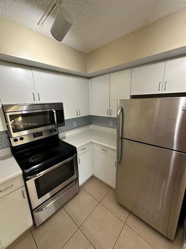 kitchen with stainless steel appliances, white cabinetry, a textured ceiling, and light tile patterned floors