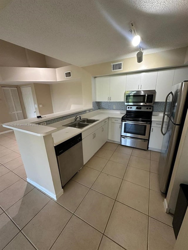 kitchen with sink, kitchen peninsula, a textured ceiling, white cabinetry, and appliances with stainless steel finishes