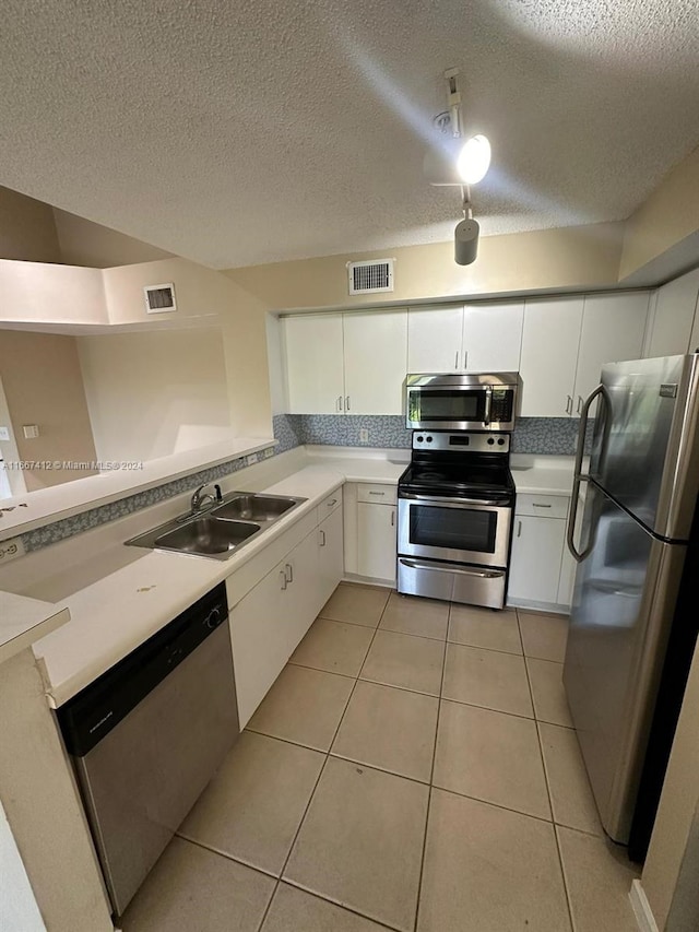 kitchen featuring light tile patterned flooring, white cabinetry, stainless steel appliances, a textured ceiling, and sink