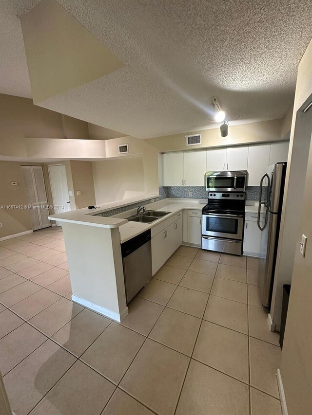 4848 N State Road 7 Unit 4305, Coconut Creek, FL 33073 - kitchen with appliances with stainless steel finishes, a textured ceiling, light tile patterned floors, white cabinets, and a peninsula