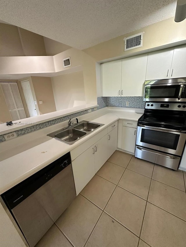 kitchen featuring a textured ceiling, sink, white cabinets, appliances with stainless steel finishes, and light tile patterned floors