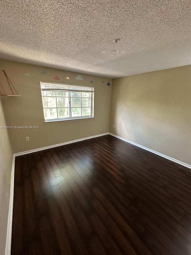 spare room featuring a textured ceiling and dark wood-type flooring