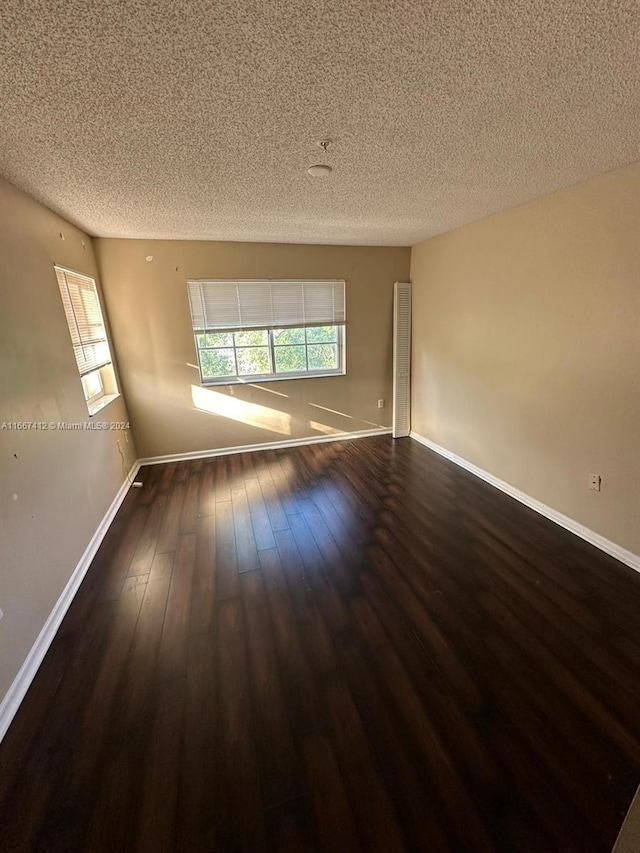 unfurnished room with a textured ceiling and dark hardwood / wood-style flooring