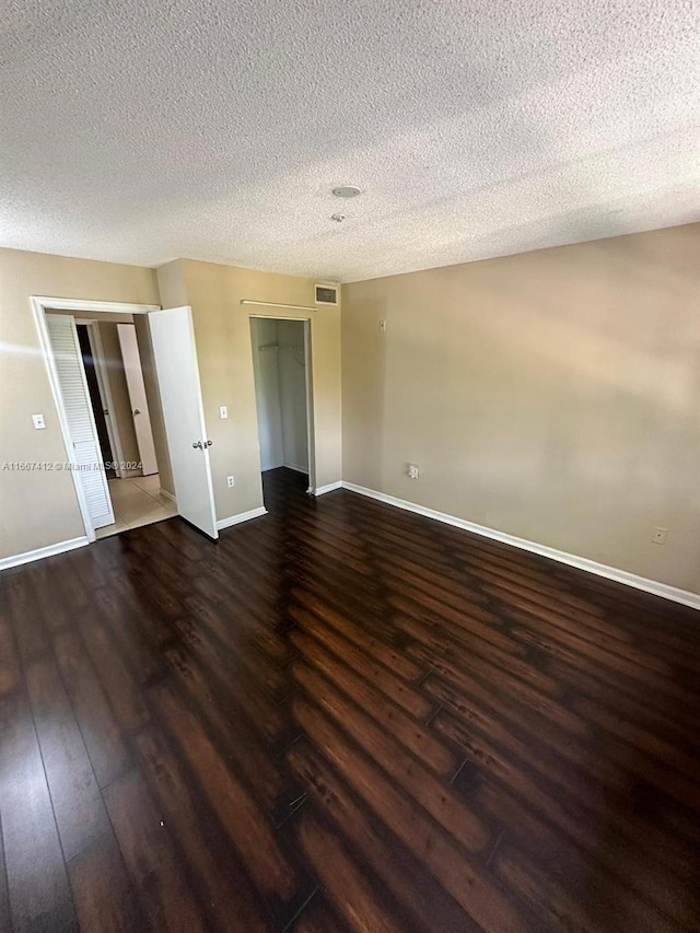 unfurnished bedroom featuring a closet, a textured ceiling, and dark wood-type flooring