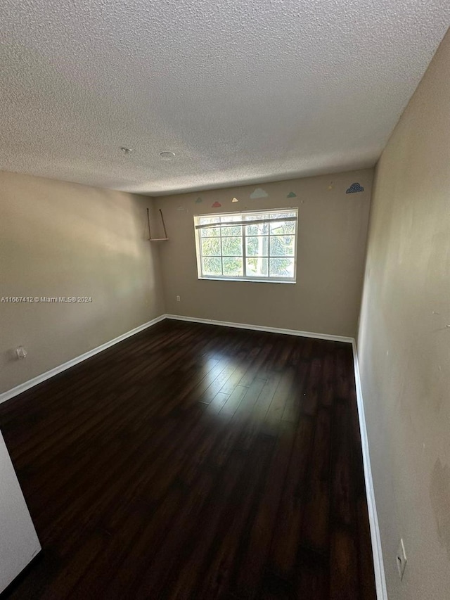 unfurnished room featuring a textured ceiling and dark hardwood / wood-style floors