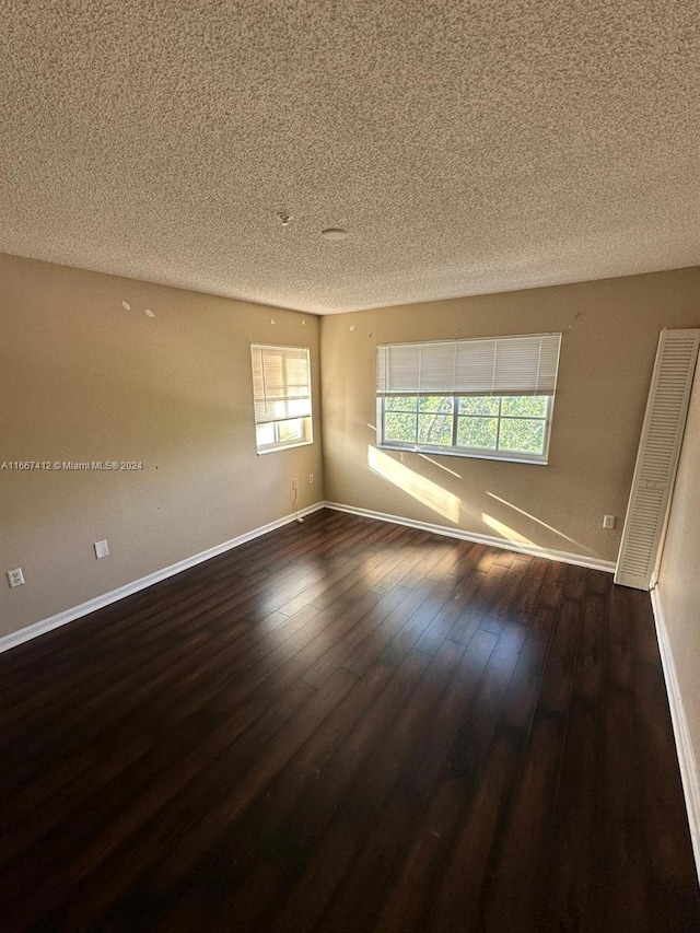 unfurnished room featuring a wealth of natural light, a textured ceiling, and dark hardwood / wood-style floors