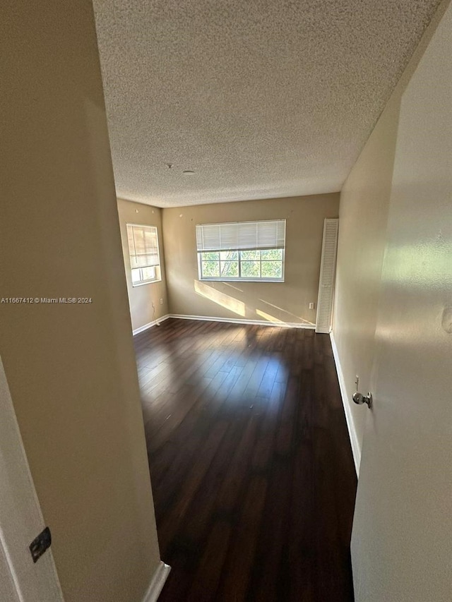 empty room with a textured ceiling and dark wood-type flooring