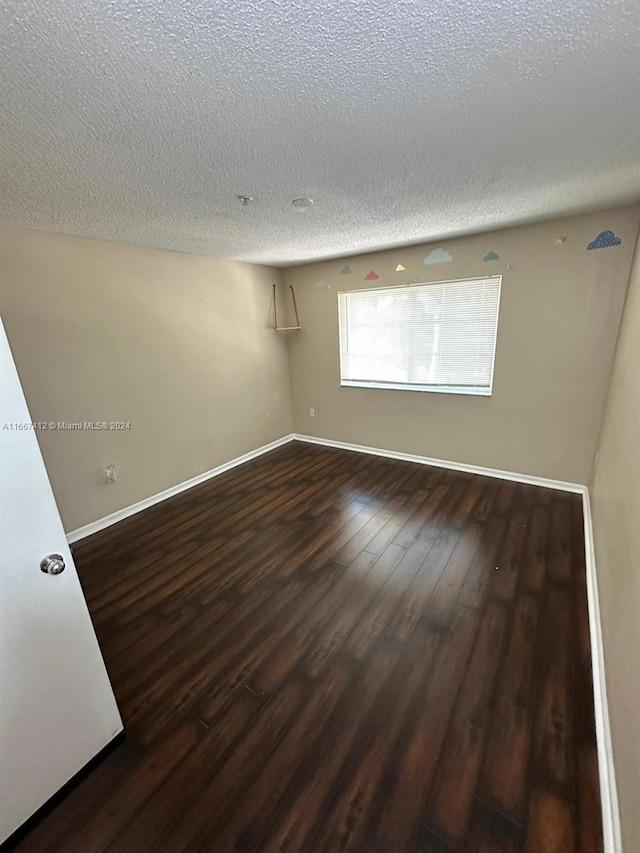 spare room featuring a textured ceiling and dark hardwood / wood-style floors