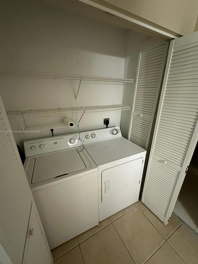 laundry area with washer and clothes dryer and light tile patterned flooring