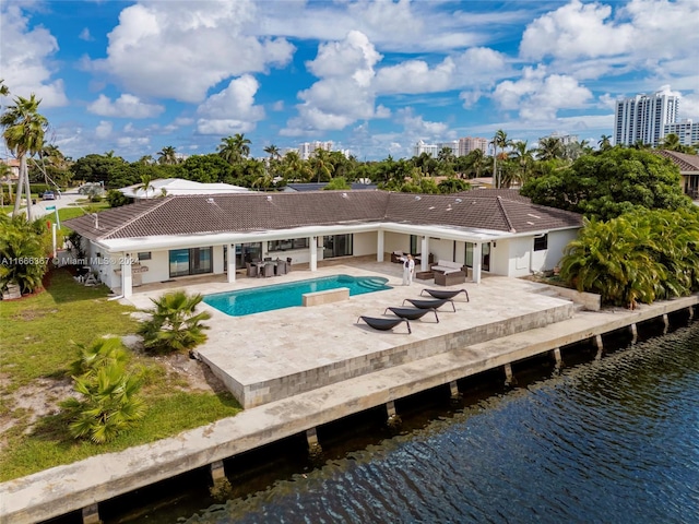 rear view of house with a water view, a yard, and a patio area