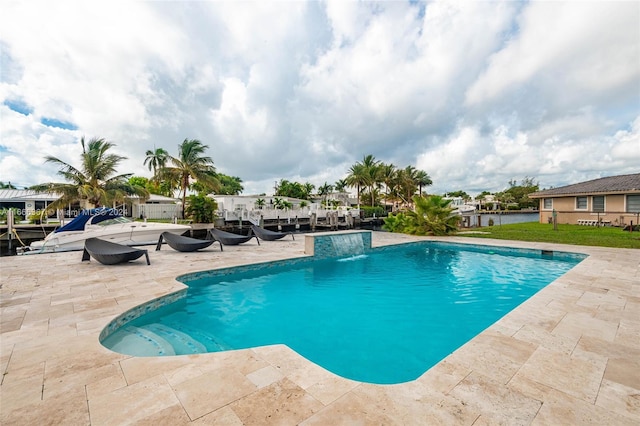 view of pool with a patio, a water view, a yard, and pool water feature