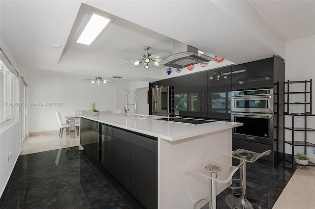 kitchen featuring stainless steel appliances, ceiling fan, dark tile patterned floors, a large island, and sink