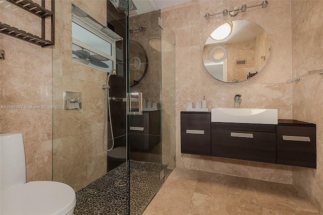 bathroom featuring a tile shower, tile walls, vanity, and toilet