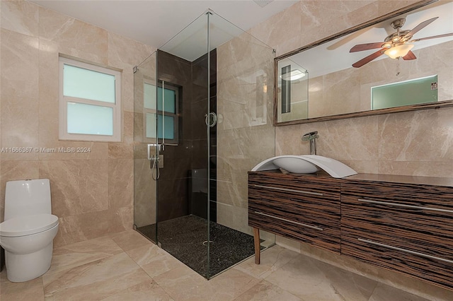 bathroom with tile walls, vanity, ceiling fan, and a shower with door