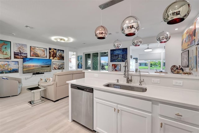 kitchen with decorative light fixtures, white cabinetry, dishwasher, sink, and light hardwood / wood-style flooring