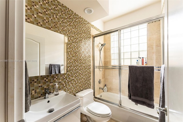 full bathroom with shower / bath combination with glass door, decorative backsplash, vanity, and toilet