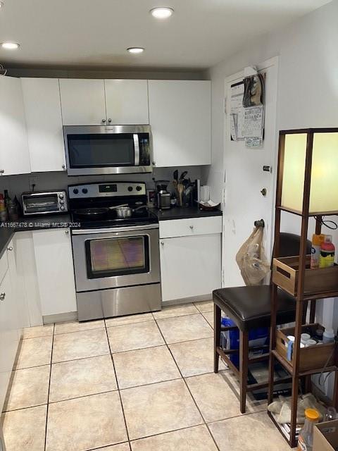 kitchen featuring light tile patterned floors, stainless steel appliances, and white cabinets