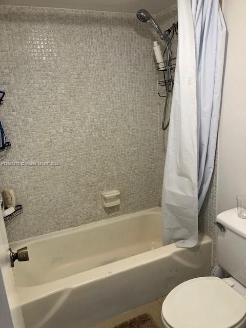 bathroom featuring shower / tub combo with curtain and toilet