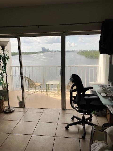 home office with a water view, a healthy amount of sunlight, and tile patterned floors